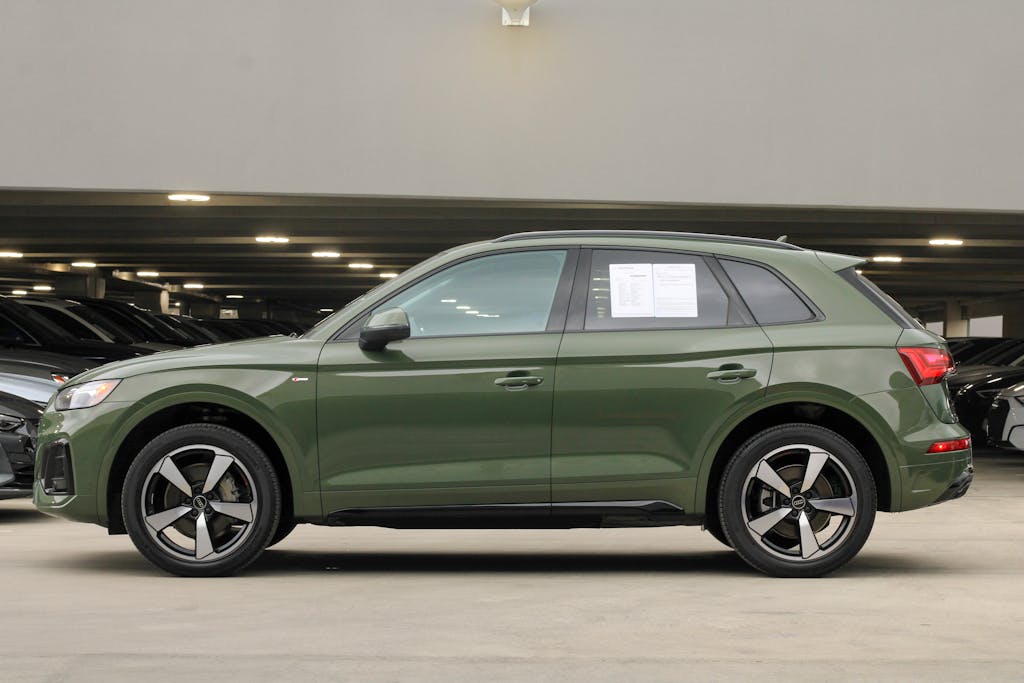 Detailed side view of a green luxury SUV in an indoor urban parking space.